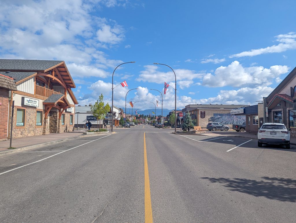A wide street in a town with buildings on each side and flags flying from light posts all the way down the road.