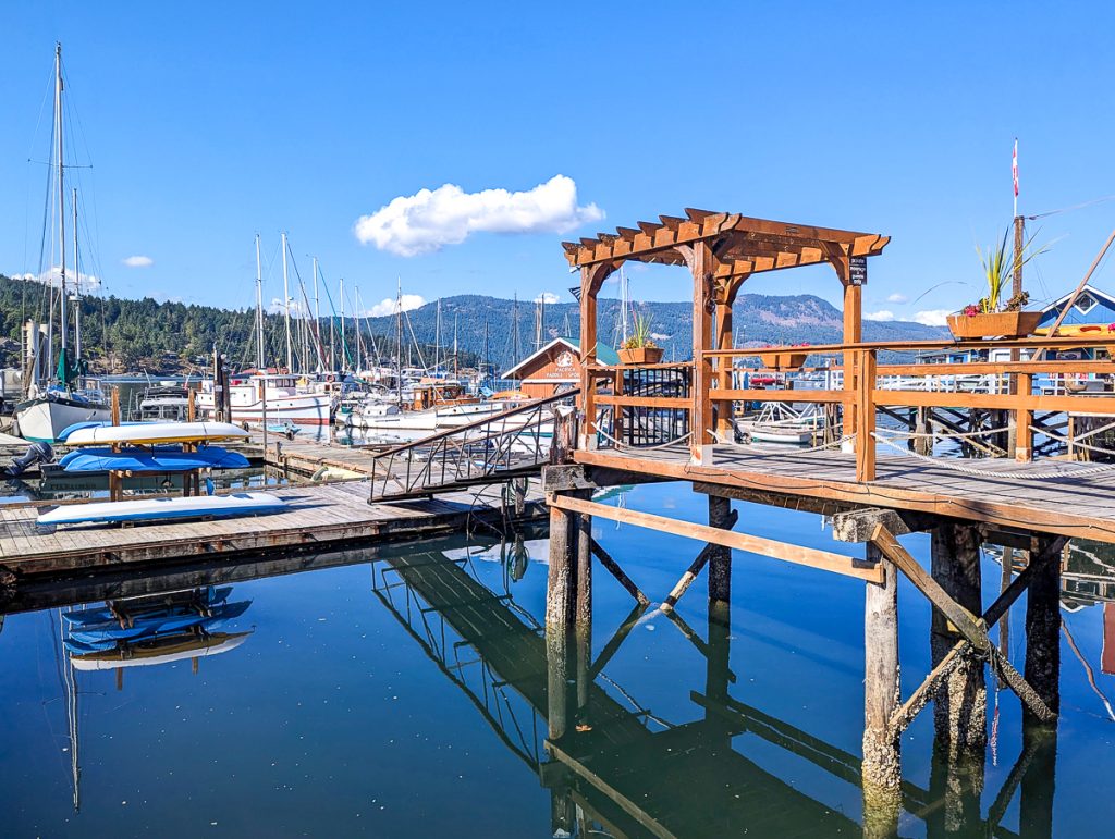 A series of wooden docks and yachts on a still harbor with blue sky reflecting into the water.