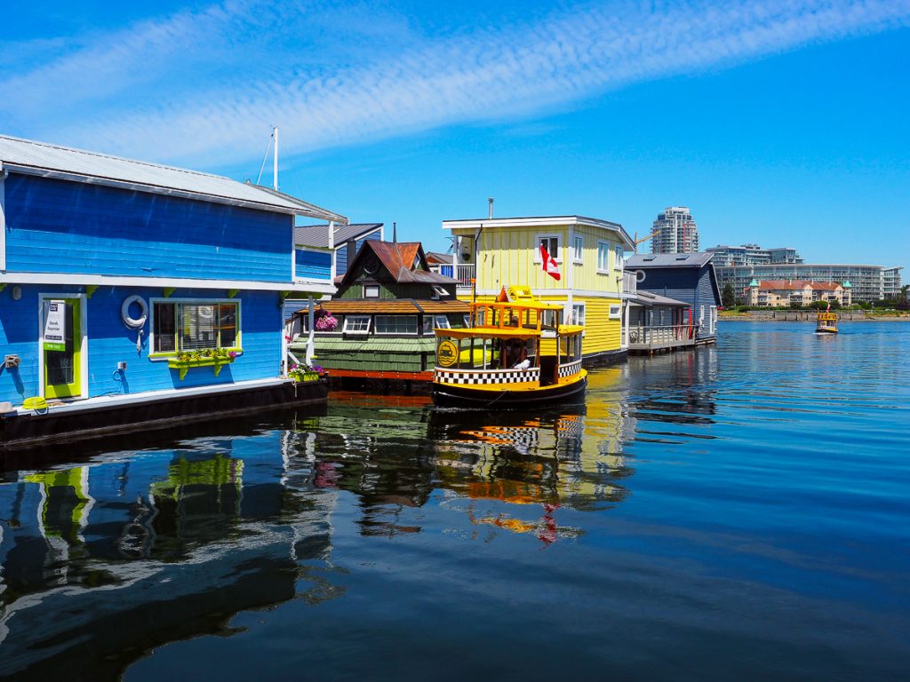 A group of colorful houseboats floating on water with a bright blue sky above.