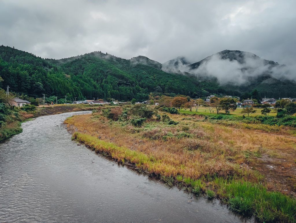 the town of Chikatsuyu with a river and mountains with gray skies