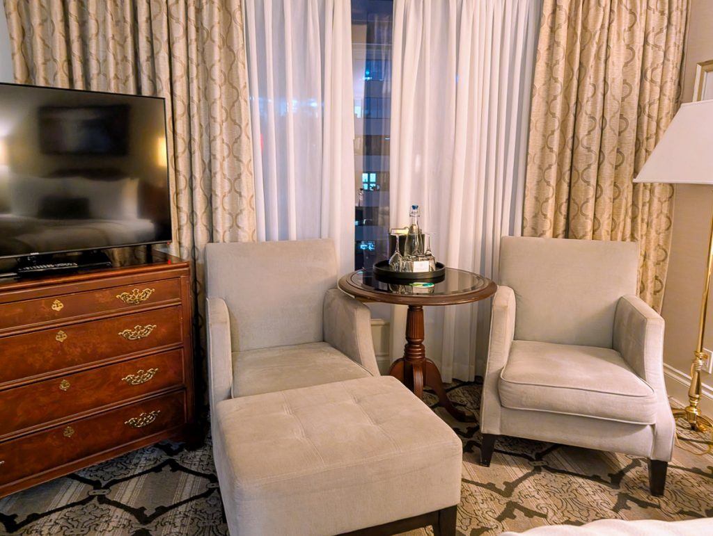 Comfy-looking lounge chairs next to a television with curtains closed behind them.
