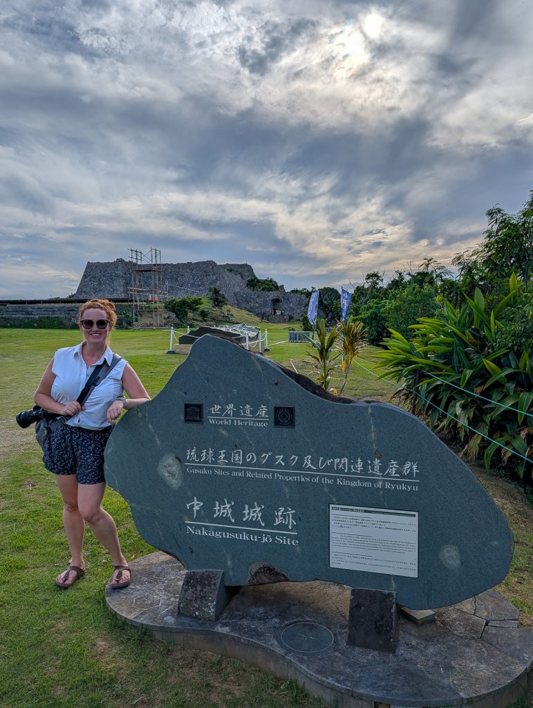Sooz leaning on a stone sign with information written in Japanese and English, and stone ruins in the background.