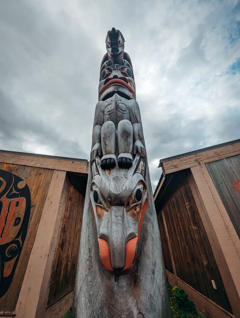 An extreme close up looking up a carved wooden totem pole with human and animal figures.