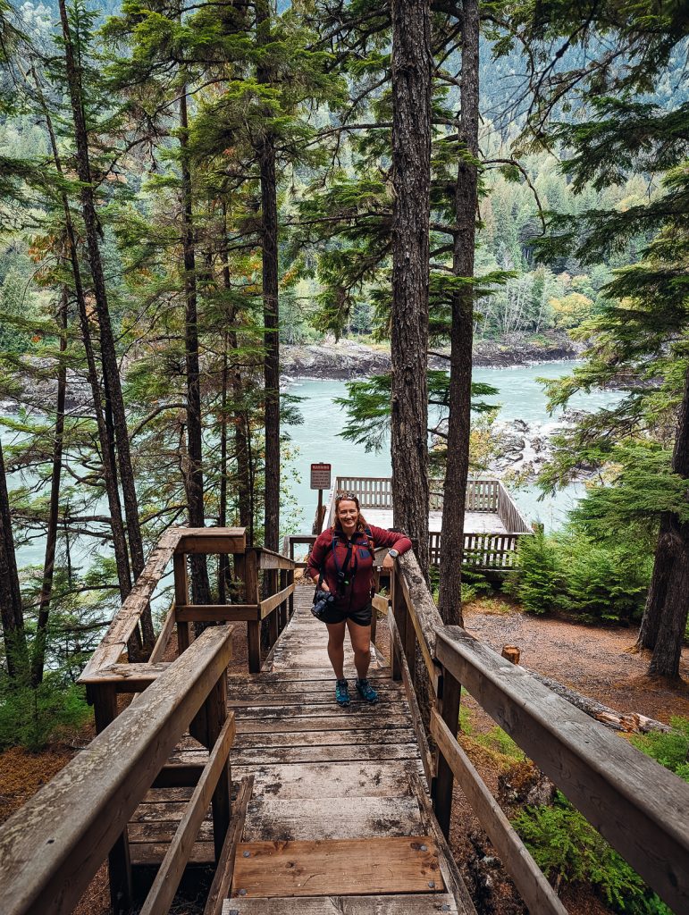 A woman standing on stairs leading down to a viewing platform over a river.