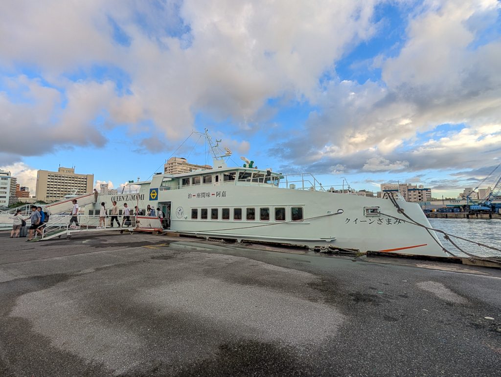 A white ferry docked under blue skies with fluffy white clouds.