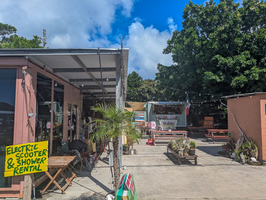The exterior of a cute and rustic restaurant on the Kerama Islands with picnic benches, string lights and plants everywhere.