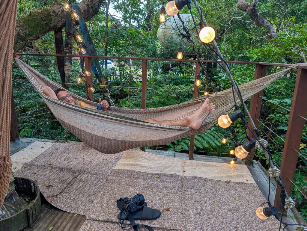 Ganesh sits in a hammock at Treeful Treehouse