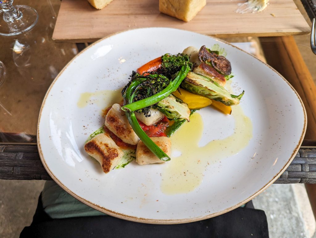An overhead close up shot of a white plate with gnocchi and vegetables.