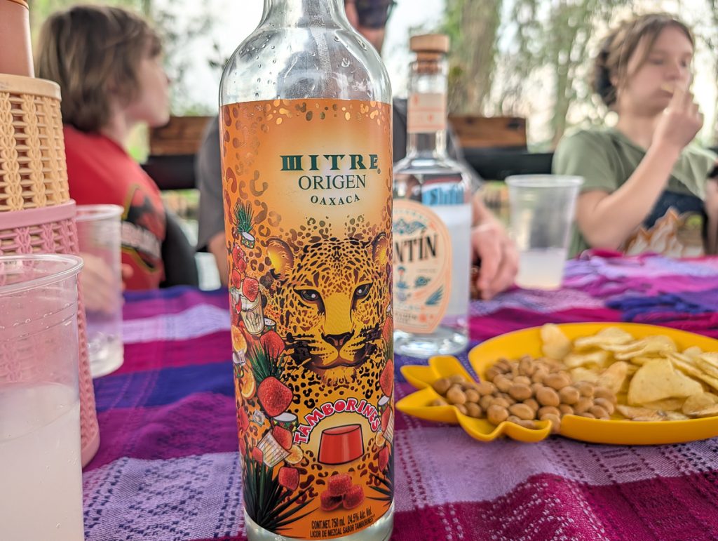 A close up shot of a bottle with a leopard on it with out of focus snacks and people in the background.