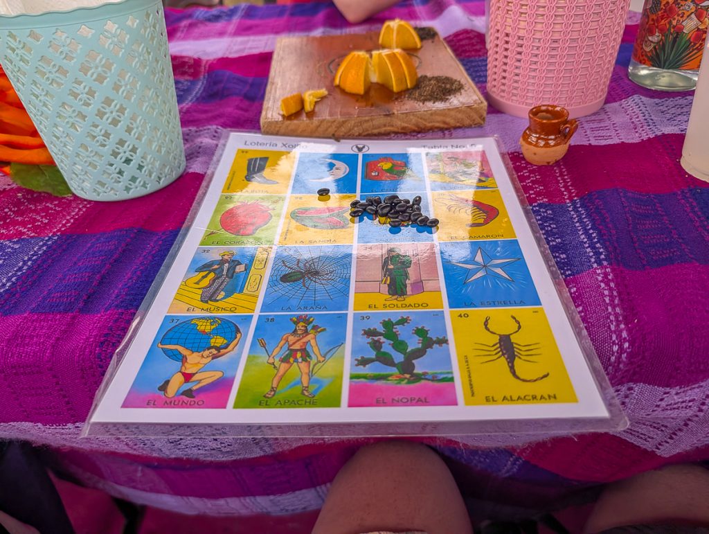 A colorful Mexican bingo board on a table with a colorful cloth on it.