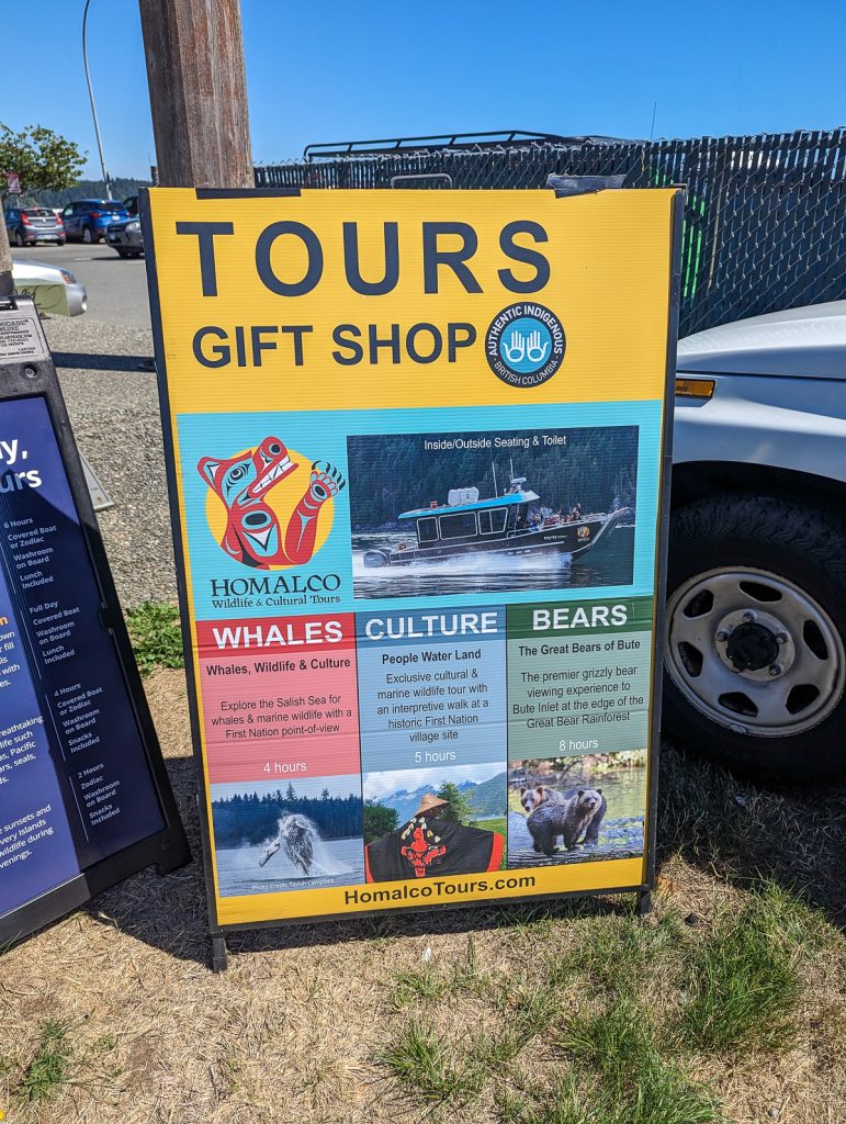 A colorful sign advertising wildlife and cultural tours and a gift shop for Homalco Tours.