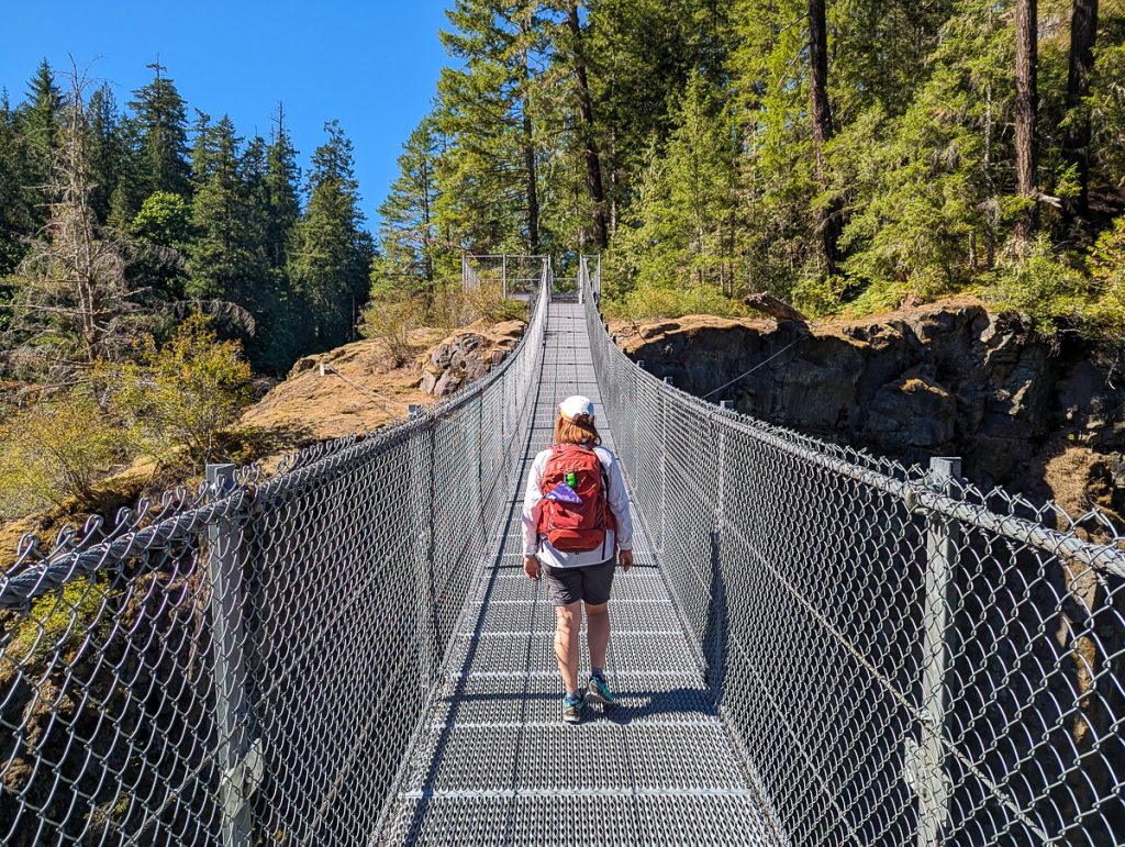A woman walks across a suspension bridge