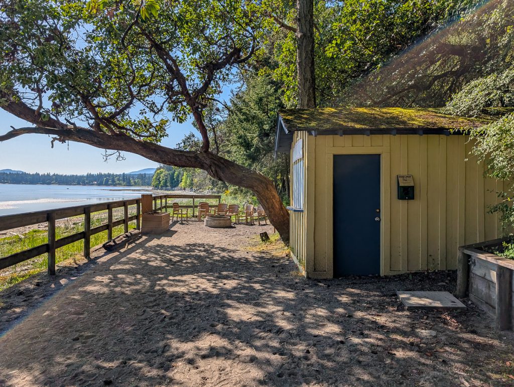 A yellow cabin next to a fire pit on the beach