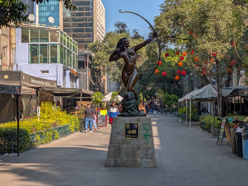 a car-free street with statues and food carts in mexico City