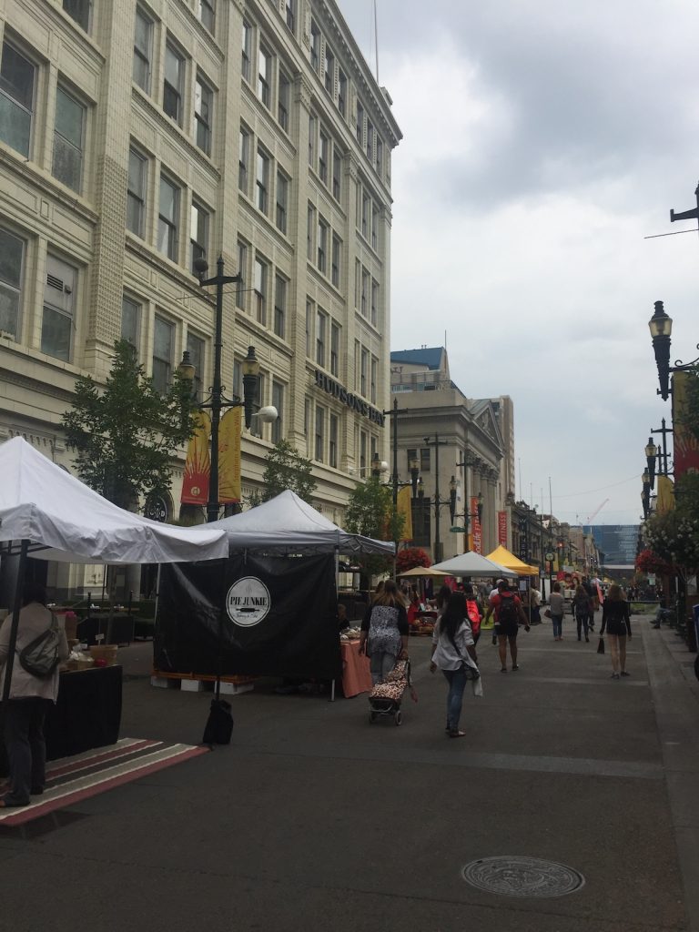 Market stalls on a pedestrian walking zone with tall buildings behind.