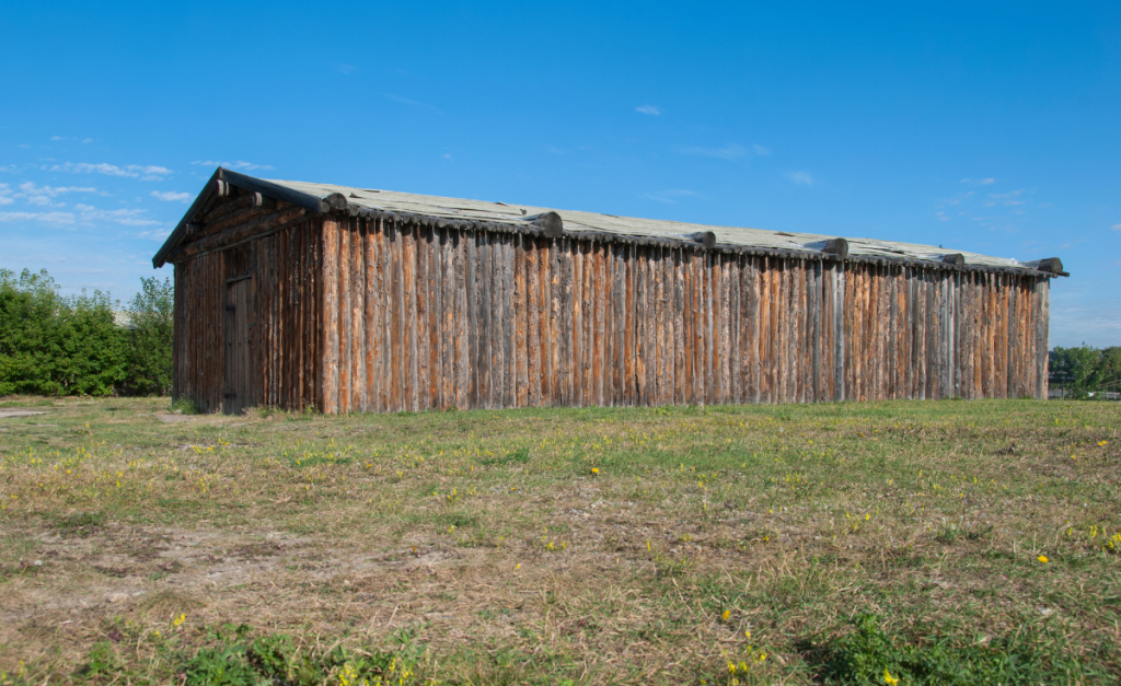 A long log building on grass with blue sky behind.