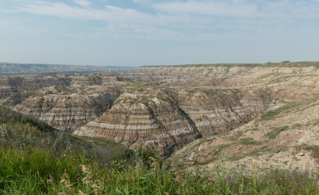 A view from on top of a canyon looking over mountains with layers of different colored rock.