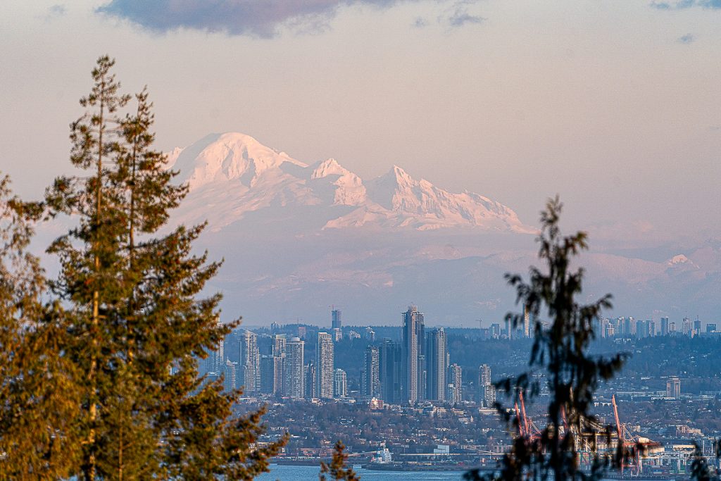 A snowy mountain , Mt. Baker, looming over the skyline of Vancouver