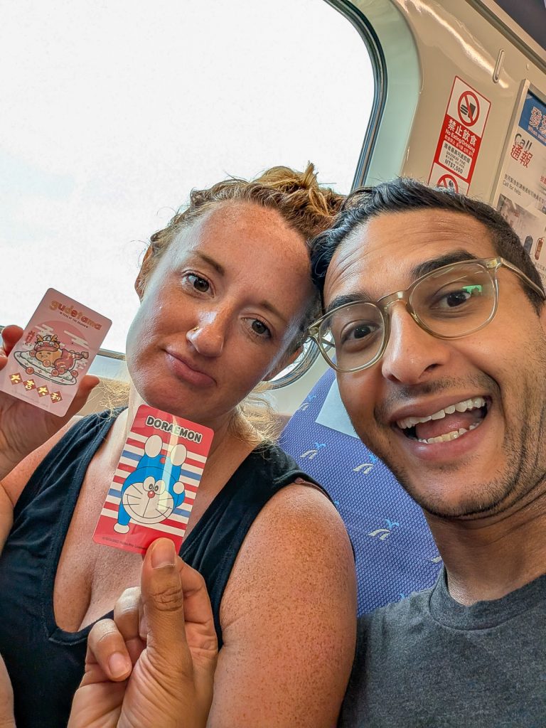 Sooz and Ganesh posing with their Taipei gudetama and Doraemon metro cards.