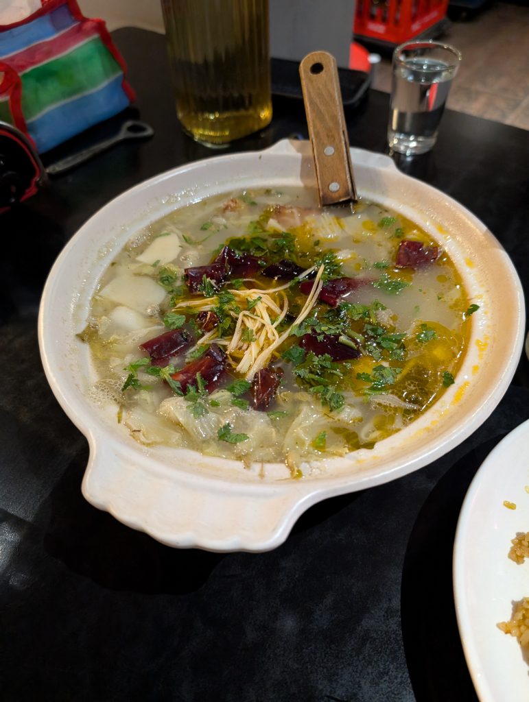 A close-up of a white bowl filled with a brothy soup of vegetables.