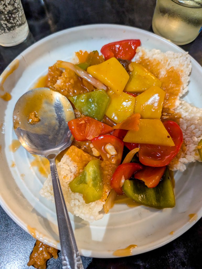 A close-up of a white plate of rice and vegetables with a spoon.