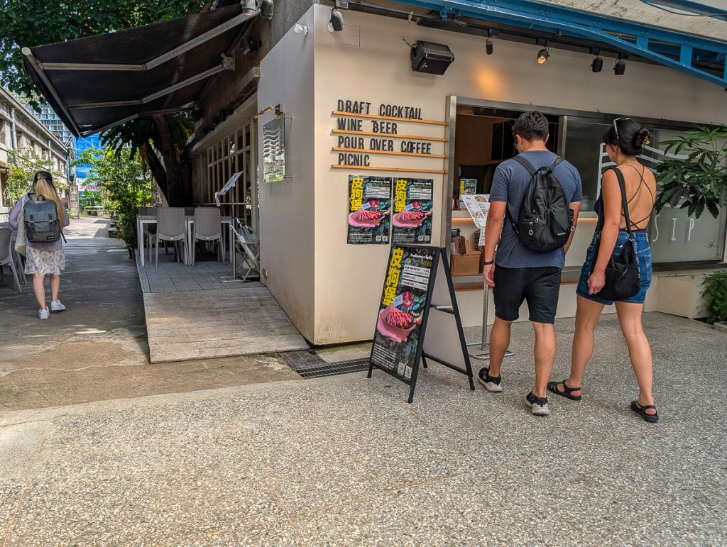 People walking up to a building with both English and Chinese signage about the drinks on offer.