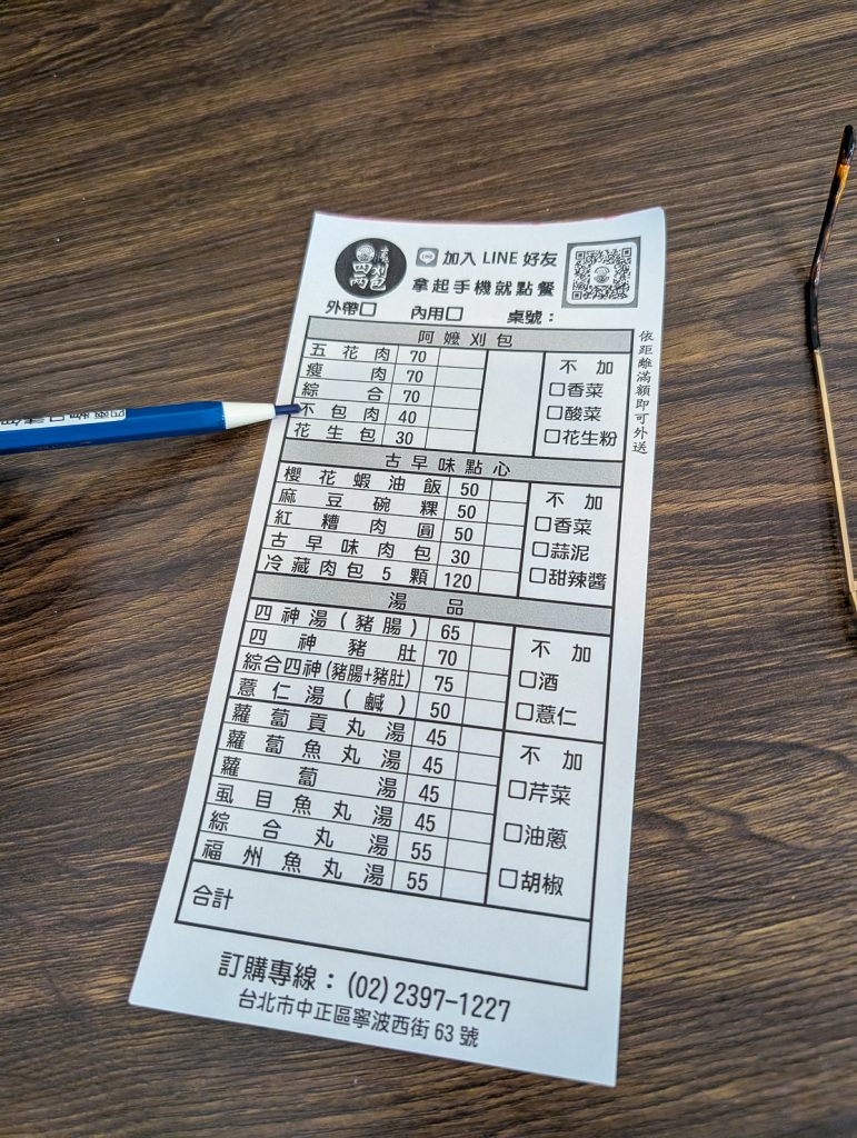A restaurant order sheet written in Chinese with a blue pencil next to it.