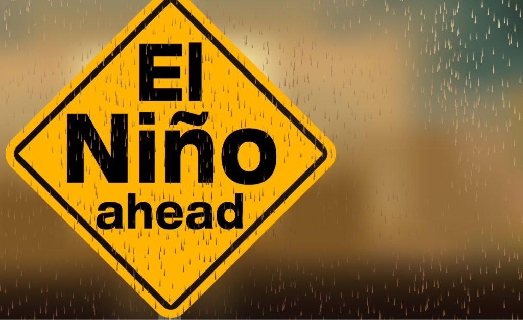 A yellow and black traffic sign with a blurred background and raindrops falling in front. The sign reads "El Niño ahead."