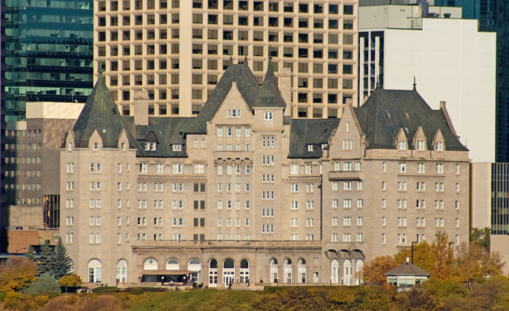 A large building with peaked roofs and turrets with skyscrapers behind.