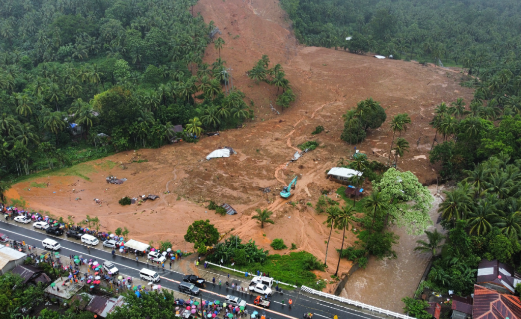 An aerial photo of a strip of mud in forest, showing the aftermath of a landslide next to a road.