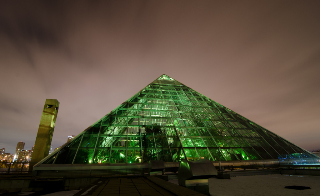 A green glass pyramid structure at night.