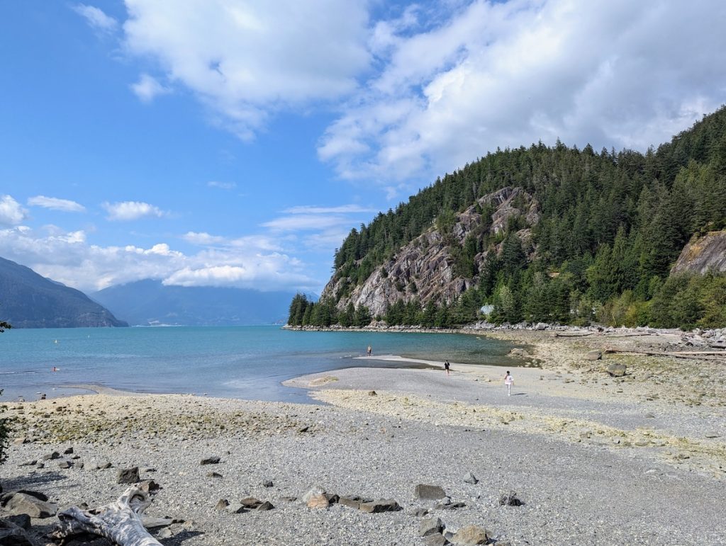 White sand beach with blue water and a mountain at porteau cove