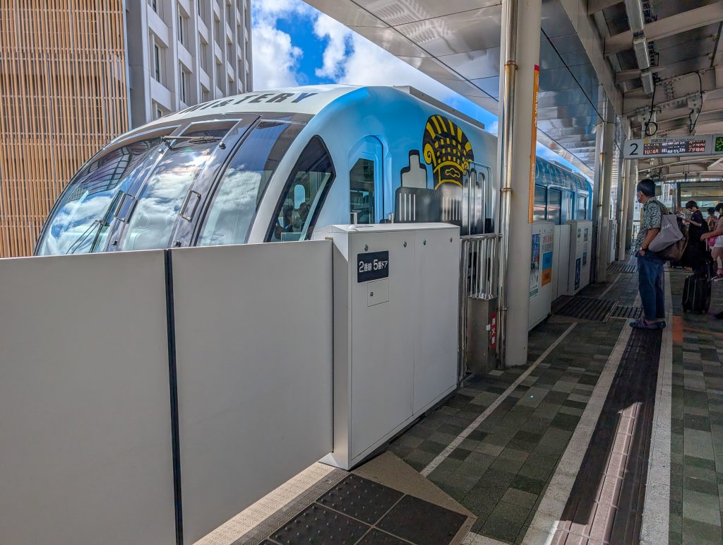 A Japanese train at a station with people standing waiting on the platform.