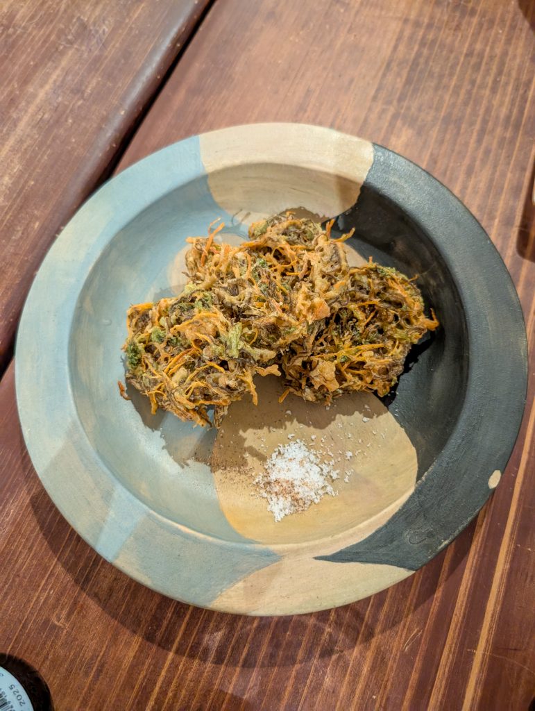 A close up overhead shot of vegetable tempura on a plate with salt.